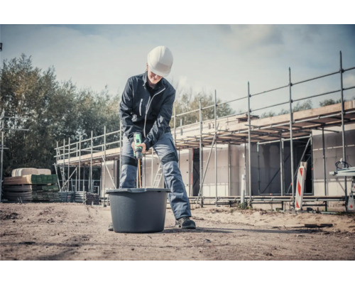 Remeselník mieša maltu miešačkou na stavenisku.