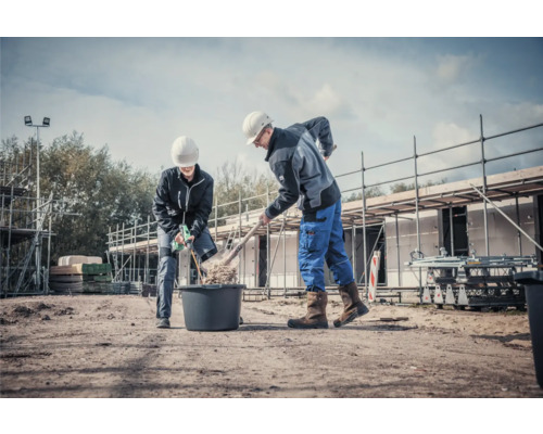 Dvaja stavební robotníci pracujú s lopatou a miešačkou na maltu na stavbe.