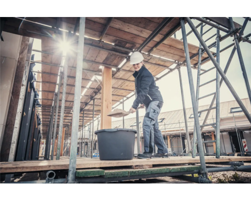 Žena s lopatou a miešacou nádobou na lešení