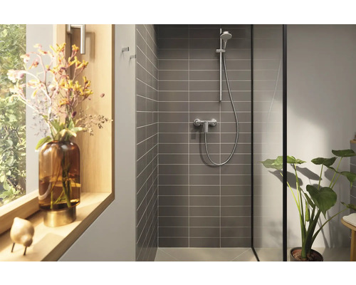 Moderný sprchovací kút so sivými obkladmi, sprchovou armatúrou a izbovou rastlinou