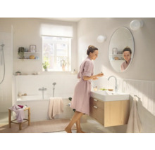 Svetlá kúpeľňa s vaňou, skrinkou pod umývadlo a ženou pred zrkadlom