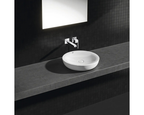 Okrúhle umývadlo na doske s armatúrou a zrkadlom na tmavej mozaikovej stene