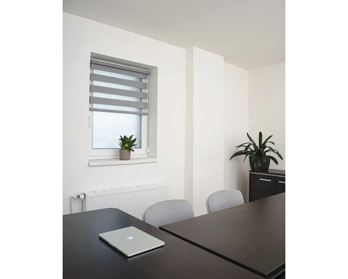 Svetlá miestnosť s oknom, roletou, stolom a notebookom