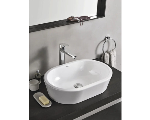 Moderné umývadlo v kúpeľni s batériou, držiakom na uteráky a doplnkami na tmavom povrchu