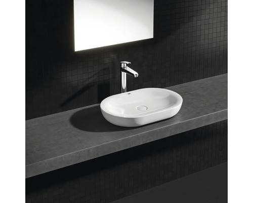 Keramické umývadlo na doske s batériou na poličke v kúpeľni.