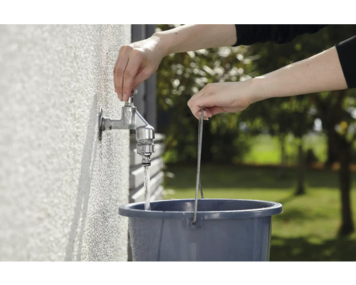 Osoba napúšťa vodu z kohútika do vedra.
