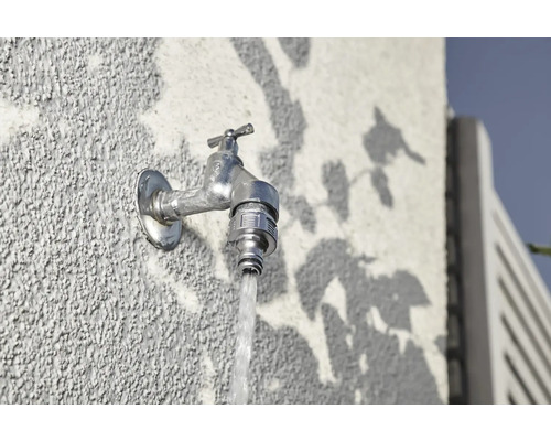 Vonkajší vodovodný kohútik na stene s tečúcou vodou