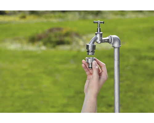 Vonkajší vodovodný kohútik s rýchlospojkou v ruke na zelenom pozadí