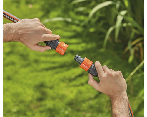 Dve ruky spájajú záhradnú hadicovú spojku.