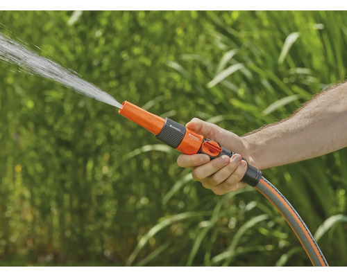 Ruka drží záhradnú sprchu, z ktorej strieka voda.