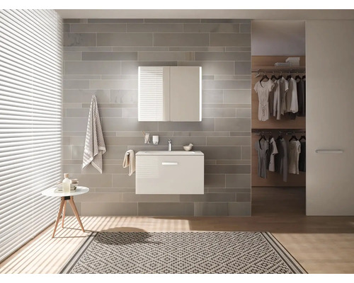 Svetlá kúpeľňa s umývadlom, zrkadlovou skrinkou, uterákmi a kobercom.