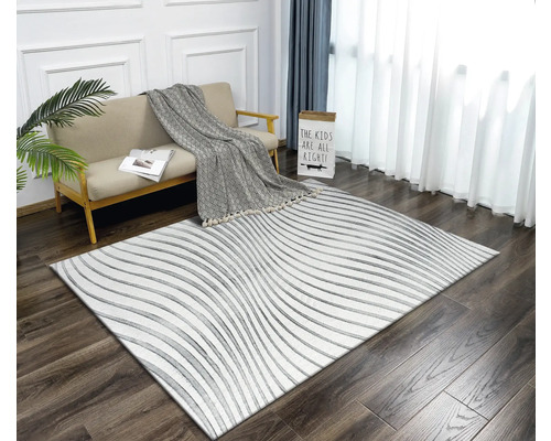 Obývacia izba s pohovkou, dekou a kobercom s lineárnym vzorom na drevenej podlahe