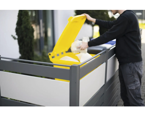 Osoba vyhadzuje odpad do žltej smetnej nádoby za zástenou