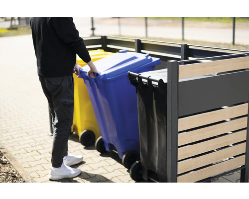 Osoba zasúva modrú smetnú nádobu do boxu na smetné nádoby