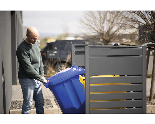 Osoba vkladá modrú smetnú nádobu do sivej skrine na smetné nádoby.