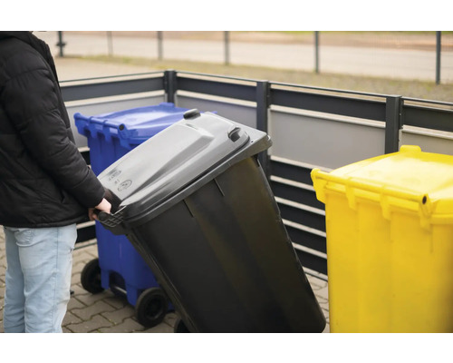 "Osoba tlačí smetnú nádobu s kolieskami