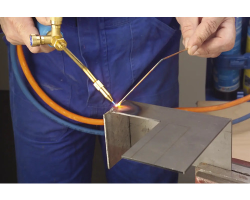 Remeselník používa spájkovaciu lampu na spracovanie kovu.