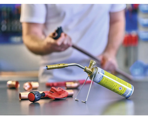 Spájkovacia lampa, medené rúry a rezačka rúrok na pracovnom stole