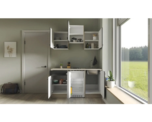 Kompaktná kuchynská linka s drezom, varnou doskou a chladničkou vo svetlej miestnosti.