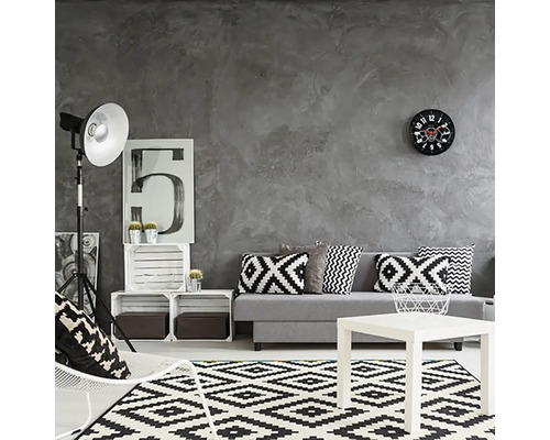 Obývacia izba so sivou stenou, pohovka s vankúšmi, koberec s geometrickým vzorom a biely konferenčný stolík.