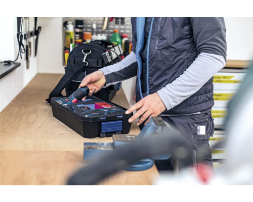 Osoba vyberá akumulátorový skrutkovač z kufríka s náradím