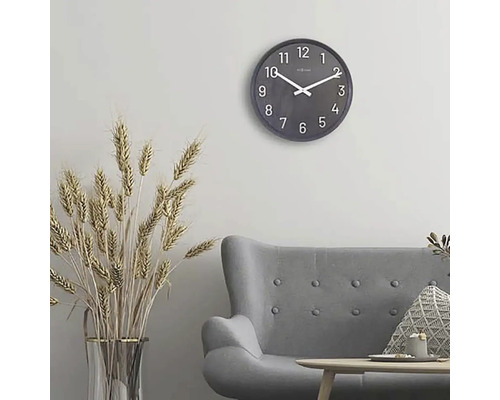 Obývacia izba so sivou pohovkou, stolom, dekoráciou a okrúhlymi nástennými hodinami