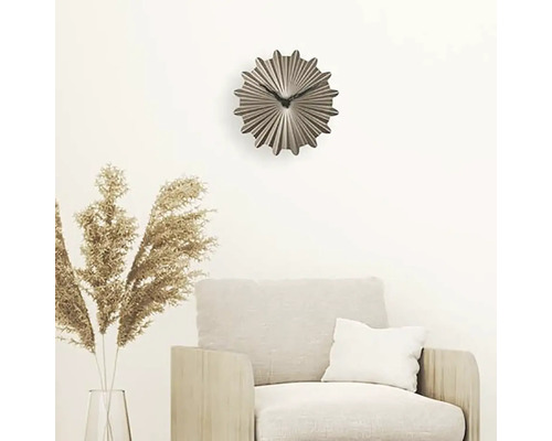 Dekoratívne nástenné hodiny nad kreslom v obývacej izbe.