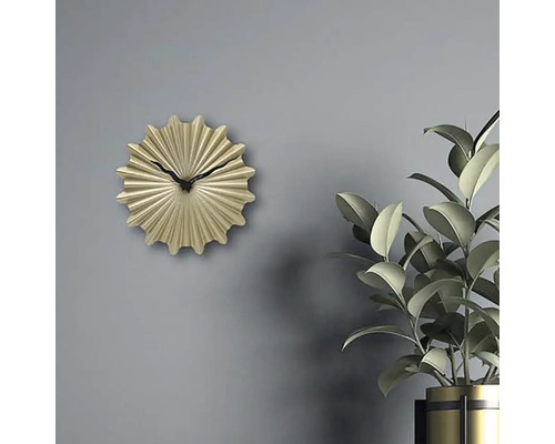 Dekoratívne zlaté nástenné hodiny s čiernou ručičkou vedľa izbovej rastliny