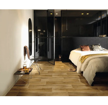 Spálňa s drevenou podlahou, posteľou a čiernymi sklenenými dverami