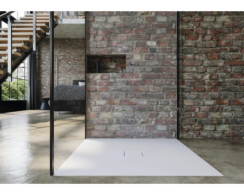 Sprchovací kút so sprchovou vaničkou pred tehlovou stenou