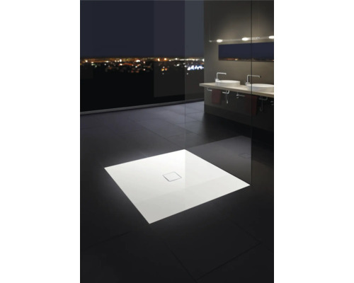 Sprchovací kút s plochou sprchovou vaničkou v modernej kúpeľni s výhľadom na nočné mesto.