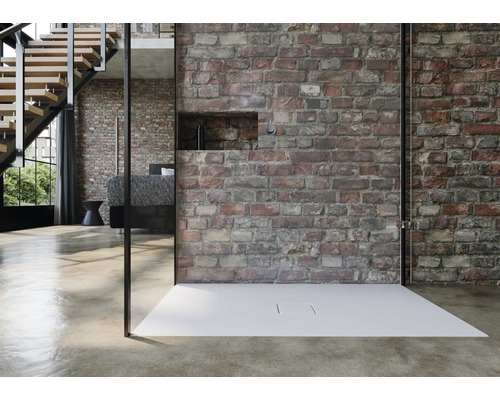 Bezbariérový sprchovací kút s plochou sprchovou vaničkou pred murovanou stenou v moderne zariadenej izbe.