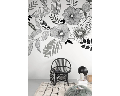 Dekoratívny obývací priestor s kvetinovou tapetou, ratanovým kreslom, kobercom a lampou