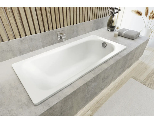 Biela vaňa zabudovaná v kúpeľni s obkladovým lemom.