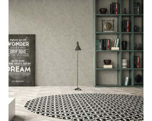 Obývacia izba s okrúhlym kobercom, stojacou lampou, regálom a dekoratívnym písmom