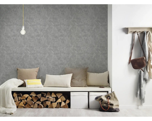 Interiér s šedou štruktúrovanou tapetou, lavicou s vankúšmi a polenami