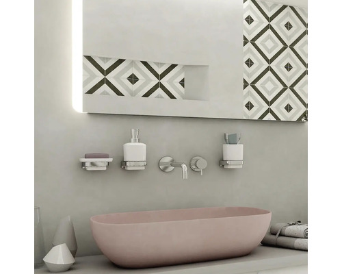 Moderná kúpeľňa s ružovým umývadlom, zrkadlom s osvetlením a rôznymi kúpeľňovými doplnkami.