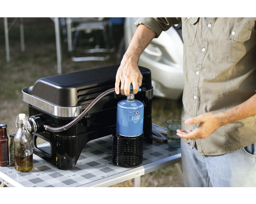 Osoba pripája plynovú fľašu ku grilu na plyn