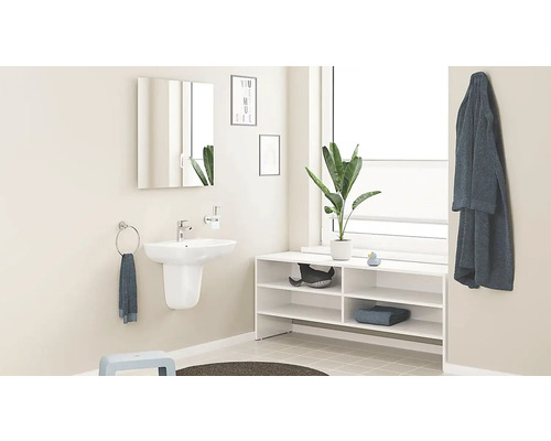 Svetlá kúpeľňa s umývadlom, zrkadlovou skriňou, regálom a dekoráciami pre organizovaný dojem.