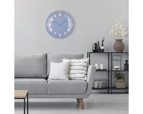 Obývacia izba so sivou pohovkou, regálom a okrúhlymi nástennými hodinami s ciferníkom