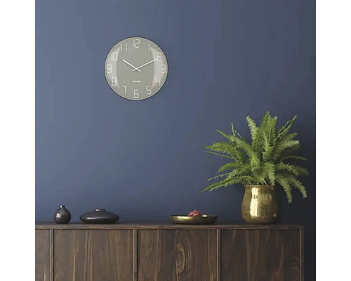 Obývacia izba s nástennými hodinami, izbovou rastlinou a drevenou komodou