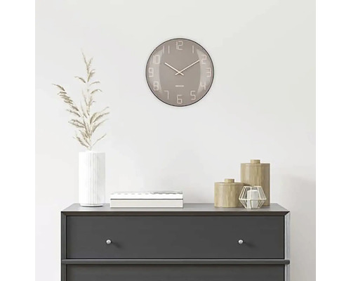 Dekoratívna scéna s okrúhlymi nástennými hodinami nad komodou.