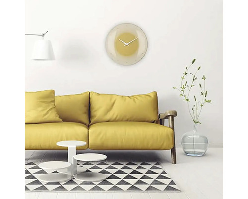 Obývacia izba so žltou pohovkou, konferenčným stolíkom, kobercom a okrúhlymi nástennými hodinami