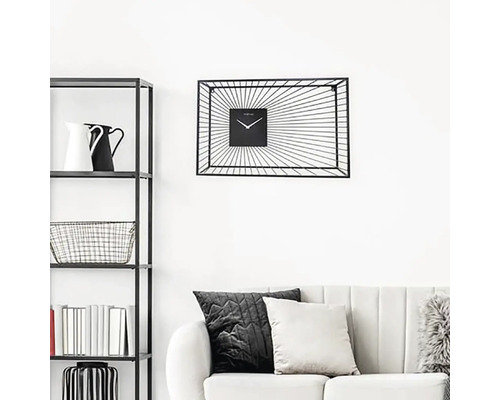 Obývacia izba s regálom, pohovkou a čiernymi nástennými hodinami