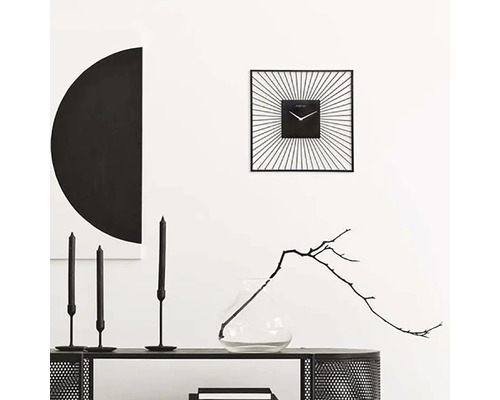 Dekoratívny interiér so štvorcovými nástennými hodinami, sviečkami a vázou s vetvičkou