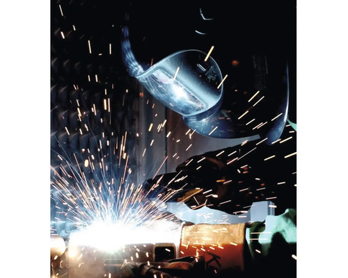 Zvárač so zváracou helmou pri práci s iskrami