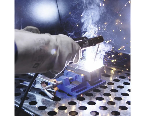 Zváranie obrobku pomocou zváračských rukavíc a zveráka