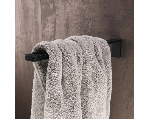 Čierny držiak na uteráky s uterákom na stene