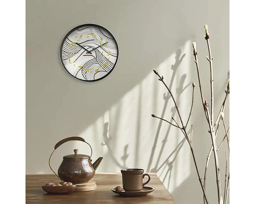 Nástenné hodiny s abstraktným vzorom nad kanvicou a šálkou na stole