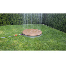 Okrúhly zavlažovač trávnika z dreva a kovu na trávniku v záhrade.